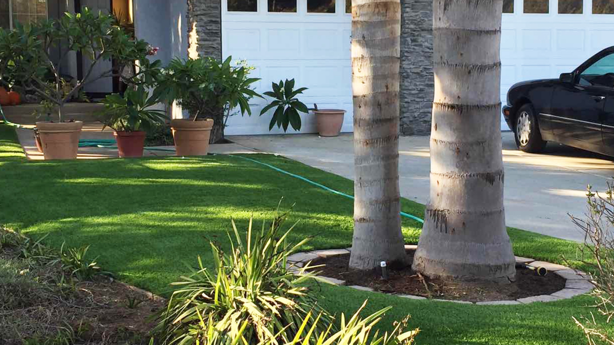 Front yard landscaping ideas landscape lawn artificial grass, synthetic turf, garden flowers palm trees, garage door, driveway