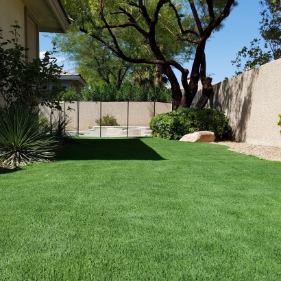 Backyard synthetic lawn artificial grass installation green landscape with shrubs by stone fence Riviera Monterey 50 M Blade shape blades