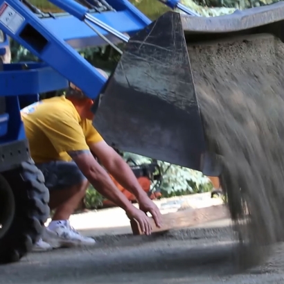 Depomposed granite truck preparing base for synthetic grass installation