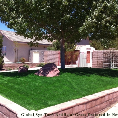 Elevated front yard green artificial grass with a tree and large rock
