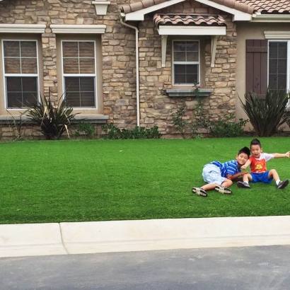 Artificial grass synthetic turf drought water children front yard playing two boys summer green grass lawn gray stone house