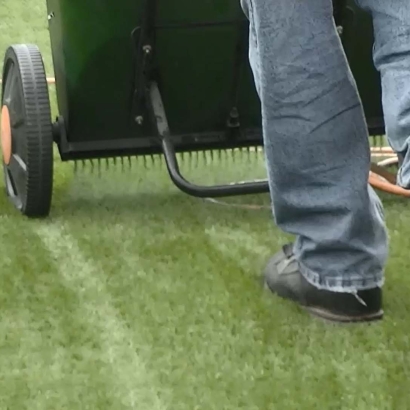 synthetic artificial grass installation man walking infilling turf