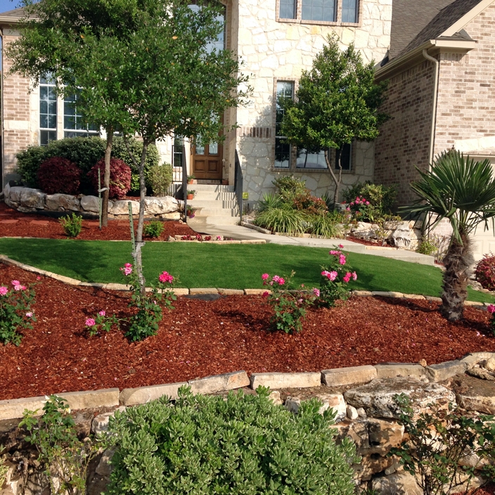 Front Yard with mulch, roses, palm tree, natural stone borders, brick house, decorative bushes