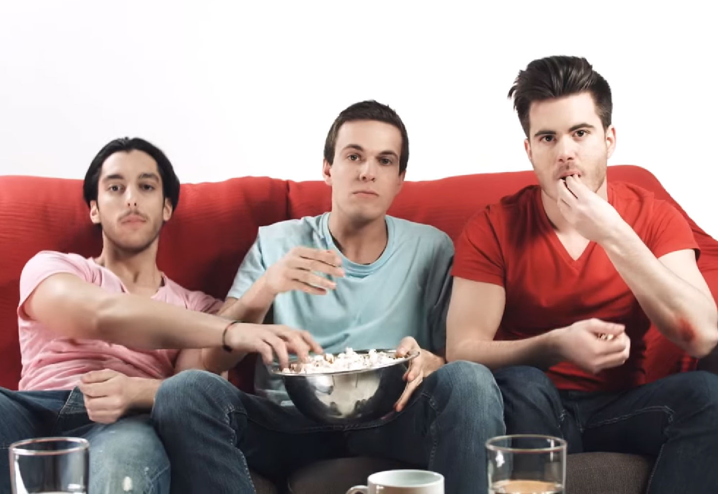 Three young man eat popcorn red counch