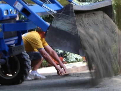 Depomposed granite truck preparing base for synthetic grass installation