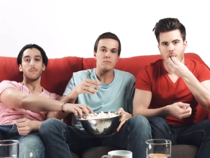 Three young man eat popcorn red counch