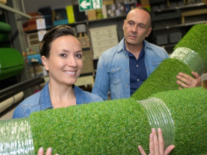 Man women holding rolls of artificial grass