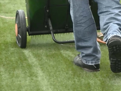 synthetic artificial grass installation man walking infilling turf