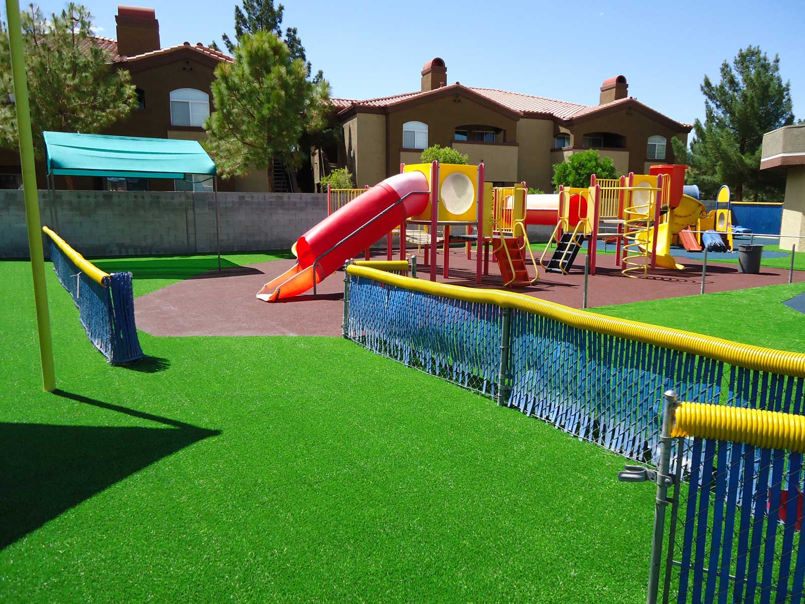 Playground surfacing or flooring, Sand, mulch, gravel, rubber, rubber tiles, mats, crumbs, artificial grass pros and cons, cost, safety, design. Green grass synthetic fake playground.